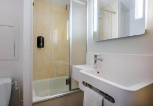 a white bathroom with a sink and a shower at B&B HOTEL FREJUS Puget-sur-Argens in Fréjus