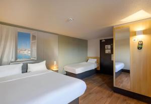 a hotel room with two beds and a window at B&B HOTEL FREJUS Puget-sur-Argens in Fréjus