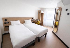 a hotel room with two beds and a mirror at B&B HOTEL Orléans Centre Foch in Orléans