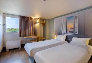 a hotel room with two beds and a window at B&B HOTEL FREJUS Puget-sur-Argens in Fréjus