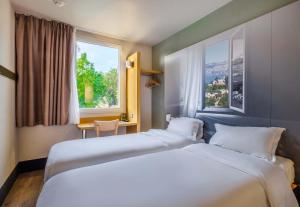 a hotel room with two beds and a window at B&B HOTEL Antibes Sophia Antipolis in Biot