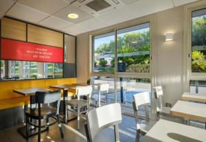 a restaurant with white chairs and tables and windows at B&B HOTEL Antibes Sophia Antipolis in Biot +18 photos