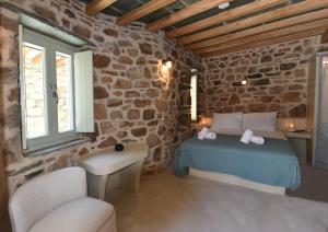 a bedroom with a bed in a room with a stone wall at Koumaros Cycladic Suites in Koumáros