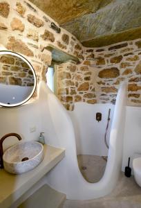a bathroom with a sink and a stone wall at Koumaros Cycladic Suites in Koumáros +42 photos