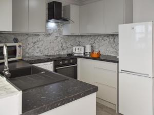 a kitchen with white appliances and a black counter top at Turnstones in Walcott