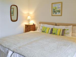 a bedroom with a large white bed with a mirror at Beuchan Cottage Keir Mill in Closeburn