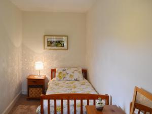 a small bedroom with a bed and a table at Beuchan Cottage Keir Mill in Closeburn