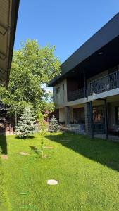 a building with a yard with a tree in front of it at Comfort Point Hotel in Bishkek