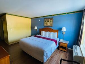 a hotel room with a large bed and blue walls at Mountain inn & suites - Dunlap TN in Dunlap