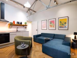 a living room with a blue couch and a kitchen at The Heim Aparthotel in Manchester