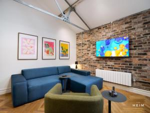 a living room with a blue couch and a brick wall at The Heim Aparthotel in Manchester