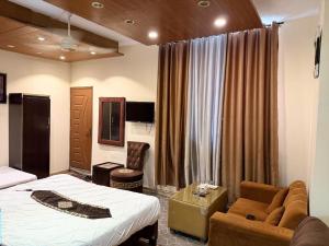 a hotel room with a bed and a couch at Palm East Hotel in Lahore