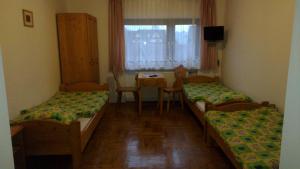 a room with two beds and a table and a window at Willa Cachro in Zakopane