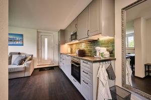 a kitchen with white cabinets and a large mirror at Clarke's Lakeside Chalet 1 in Leissigen