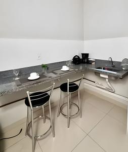 a kitchen with two chairs and a counter top at Studio #3 Rubi in Campos dos Goytacazes