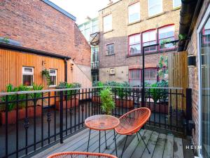 a balcony with two tables and chairs and buildings at The Heim Aparthotel in Manchester