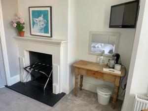 a room with a fireplace with a table and a mirror at Poplars Farm in Henlow