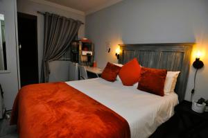 a bedroom with a large bed with orange pillows at PhysEQFiT Guesthouse in Centurion