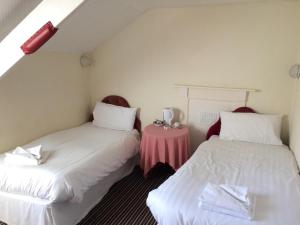 two beds in a room with a pink table at Lockyer House B&B in Plymouth