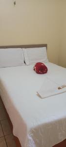 a white bed with a red hat on it at Pousada Rotamar in Paraipaba