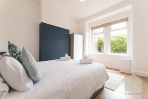 a bedroom with a large white bed with a window at Gordan Villas in Leigh