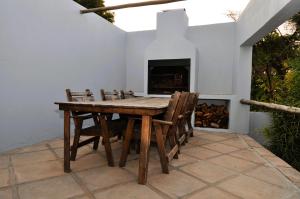 a wooden table and chairs on a patio with a fireplace at PhysEQFiT Guesthouse in Centurion