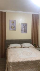 a bed in a bedroom with three pictures on the wall at Pousada Rotamar in Paraipaba