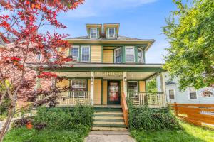 a yellow house with a porch and stairs at Stay with Jay - Quarta Suite in Cleveland