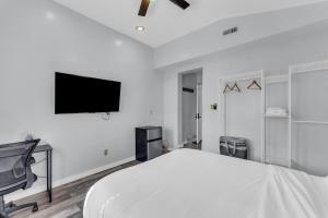 a white bedroom with a bed and a flat screen tv at Stay with Jay - Quarta Suite in Cleveland
