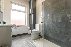 a bathroom with a toilet and a glass shower at Urmston House in Leigh
