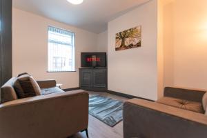 a living room with two couches and a tv at Urmston House in Leigh