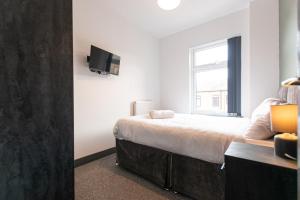 a bedroom with a bed and a tv on the wall at Urmston House in Leigh +2 photos