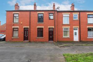 a red brick building with two doors and a parking lot at Urmston House in Leigh