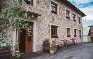 a stone building with tables and chairs in front of it at Hostinec pod úbočou in Valaská