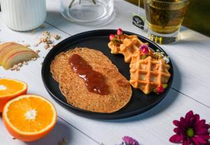 a plate with waffles and syrup and oranges on a table at B&B HOTEL Dreux Nord in Dreux +20 photos