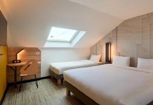 a hotel room with two beds and a skylight at B&B HOTEL Saint-Witz Roissy in Saint-Witz