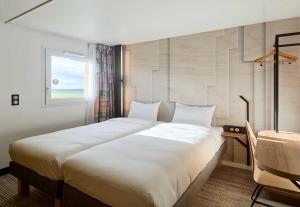 a large white bed in a room with a window at B&B HOTEL Saint-Witz Roissy in Saint-Witz