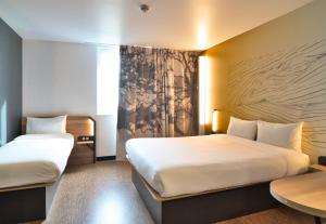 a hotel room with two beds and a table at B&B HOTEL Dreux Nord in Dreux