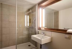 a bathroom with a sink and a shower with a mirror at B&B HOTEL Saint-Witz Roissy in Saint-Witz +34 photos