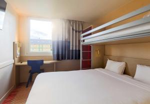 a bedroom with a bed and a desk and a window at B&B HOTEL Saint-Witz Roissy in Saint-Witz