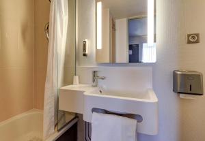 a white bathroom with a sink and a mirror at B&B HOTEL Dijon Marsannay in Marsannay-la-Côte