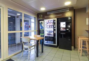 a restaurant with a table and chairs and a drink machine at B&B HOTEL Dijon Marsannay in Marsannay-la-Côte +21 photos