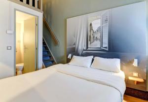 a bedroom with a white bed with a picture on the wall at B&B HOTEL Dijon Marsannay in Marsannay-la-Côte