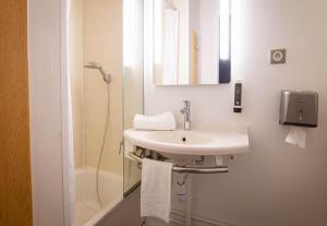 a white bathroom with a sink and a shower at B&B HOTEL Avignon 1 in Le Pontet