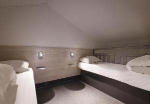 a bedroom with two beds and two lights on the wall at B&B HOTEL Avignon 1 in Le Pontet