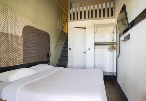 a bedroom with a white bed and a staircase at B&B HOTEL Avignon 1 in Le Pontet