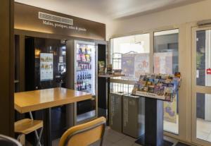 a restaurant with a counter and a table and a refrigerator at B&B HOTEL Avignon 1 in Le Pontet +34 photos