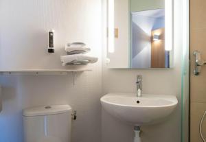 a bathroom with a sink and a toilet and a mirror at B&B HOTEL Avignon 2 in Le Pontet