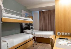 a small room with two bunk beds and a desk at B&B HOTEL Avignon 2 in Le Pontet