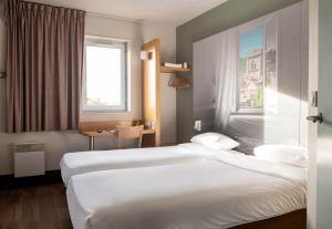 a hotel room with two beds and a window at B&B HOTEL Avignon 2 in Le Pontet